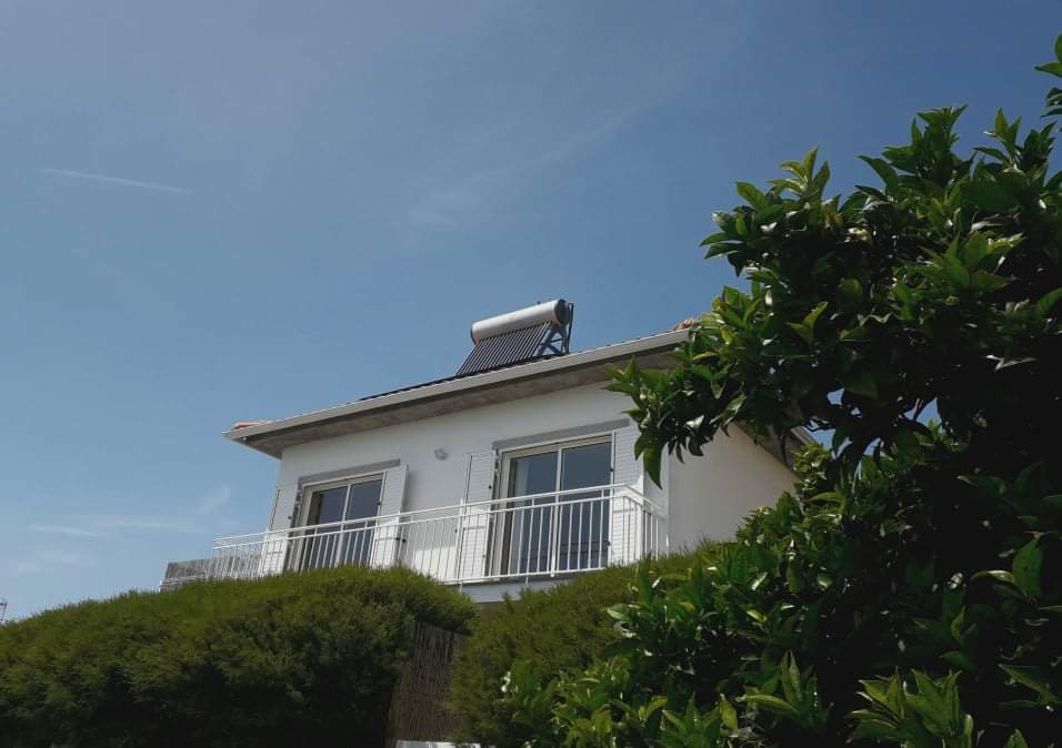 Fachada sul do Portucellus House com céu azul, varanda branca e vegetação